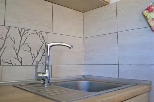 a kitchen sink with a faucet on a tiled wall at Ubytování pod Stolovou in Kunčice pod Ondřejníkem