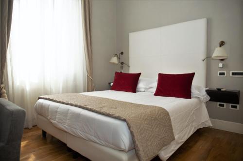 a bedroom with a large white bed with red pillows at Hotel Clitunno in Spoleto