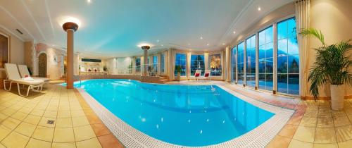 a large swimming pool in a house with a large window at Alpenhotel Stefanie - direkt buchbar in Mayrhofen
