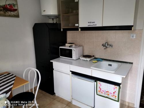 a small kitchen with a sink and a microwave at Paksy Apartman in Harkány