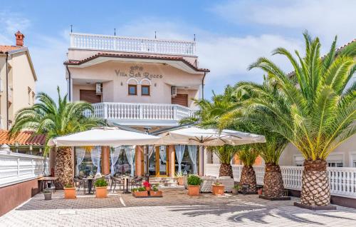 a hotel with palm trees in front of a building at Villa San Rocco Bed & Breakfast in Medulin