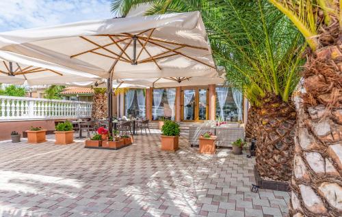 a patio with a white umbrella and a palm tree at Villa San Rocco Bed & Breakfast in Medulin