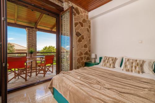 a bedroom with a bed and a balcony with a table at Villa La Isla with Private Pool in Mouzákion