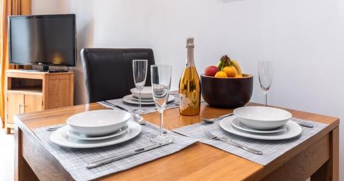 una mesa con platos y copas y una botella de vino en The Old Library - Modern apartment with rooftop terrace near the train station, en Newbury