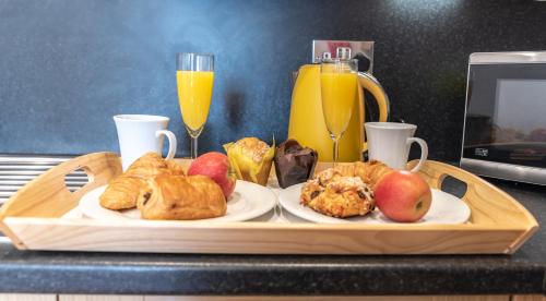a tray of breakfast foods on a counter with two glasses of orange juice at The Old Library - Modern apartment with rooftop terrace near the train station in Newbury