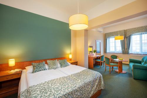 um quarto de hotel com uma cama, uma mesa e cadeiras em Hotel Bílý jednorožec em Třeboň