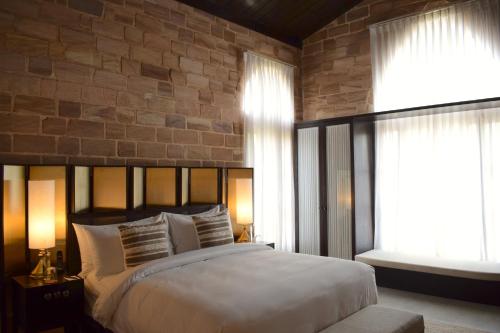 a bedroom with a large bed and a brick wall at The Postcard Gir Wildlife Sanctuary in Sasan Gir