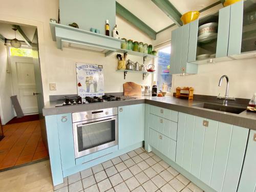 a kitchen with blue cabinets and a sink at The New Fisherman’s House in Zandvoort