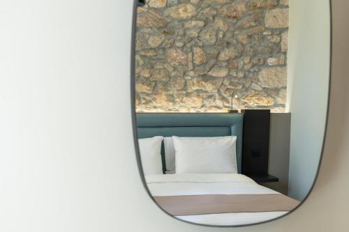 a mirror reflection of a bed with a stone wall at Philia Boutique Hotel in Athens