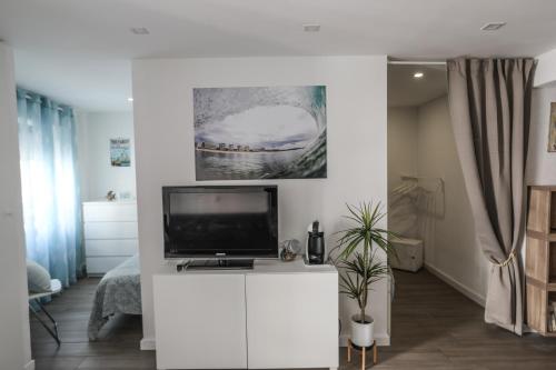 a living room with a tv on a white cabinet at Vina's Beach House - 2 minute walk to the beach in Costa da Caparica
