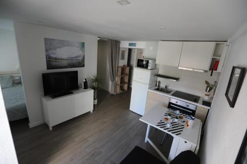 a small kitchen and living room with white cabinets at Vina's Beach House - 2 minute walk to the beach in Costa da Caparica