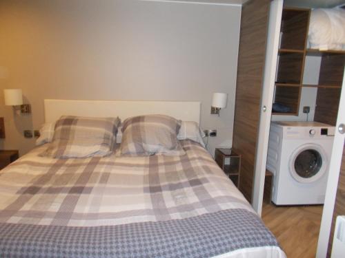 um quarto com uma cama e uma máquina de lavar roupa em mobilhome charme funpass et wifi inclus em Gastes