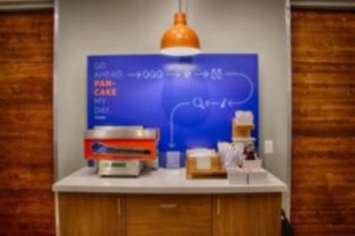 a counter with a blue board with food on it at Holiday Inn Express - Minneapolis West - Plymouth by IHG in Plymouth