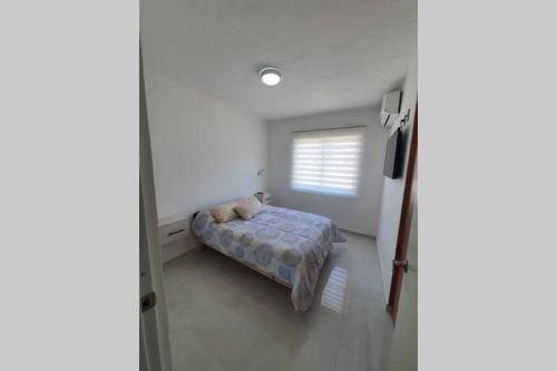 a small bedroom with a bed and a window at Departamento de lujo en Manzanillo, planta baja frente a la alberca in Manzanillo