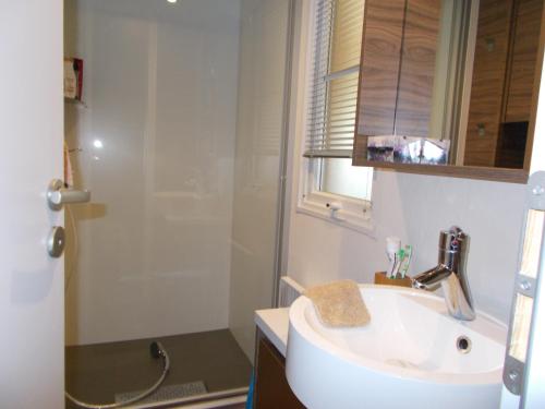 a white bathroom with a sink and a shower at mobilhome charme funpass et wifi inclus in Gastes