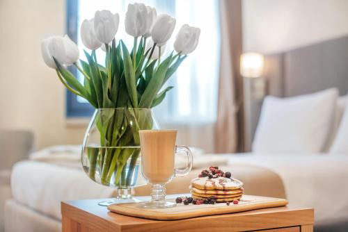 a table with a vase of tulips and a drink and a plate at Meta Business Hotel By King David in Tbilisi City
