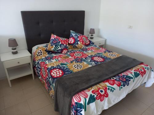 uma cama com um edredão colorido e almofadas em Apartamento Green Park Relax em San Miguel de Abona