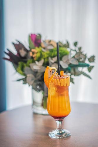a glass of orange juice on a table with a vase of flowers at Meta Business Hotel By King David in Tbilisi City