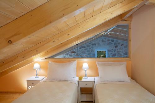 two beds in a attic room with a window at Pnoes Villas Vasiliki Lefkada in Vasiliki