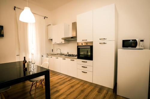 eine Küche mit weißen Schränken und einem Kühlschrank in der Unterkunft Hostly - Nicole Apartment Pontedera - 2BR in Full Center in Pontedera
