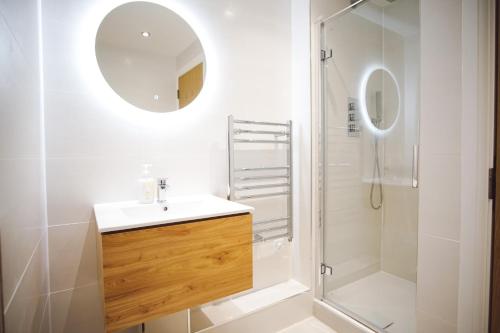 a bathroom with a sink and a shower with a mirror at Stunning Two Bed Sea View Apartment with Pool & Gym in Newquay