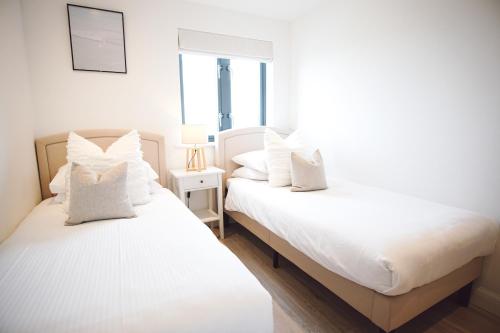 dos camas sentadas una al lado de la otra en un dormitorio en Stunning Two Bed Sea View Apartment with Pool & Gym en Newquay