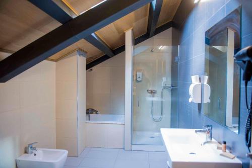 a bathroom with a shower and two sinks and a toilet at Hotel Meson de Erosa in Herosa