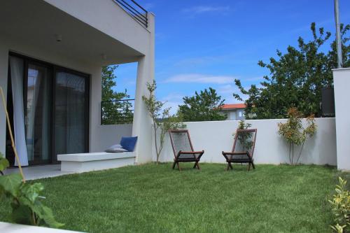 two chairs sitting in a yard next to a fence at aella apartments in Nikiti