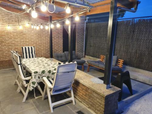 a patio with a table and chairs and lights at De Bosrand in Ichtegem