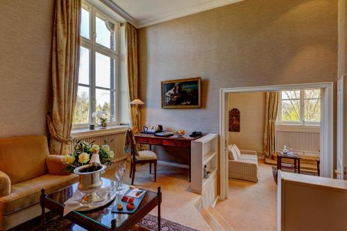 a living room with a couch and a desk in a room at Schlosshotel Hugenpoet in Essen