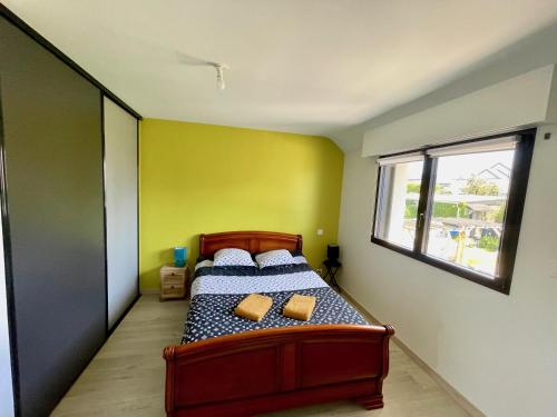 ein Schlafzimmer mit einem Bett mit gelben Wänden und einem Fenster in der Unterkunft maison moderne à guidel plage in Guidel