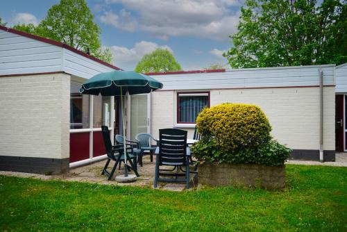 a patio with chairs and an umbrella in front of a house at Vakantie Zuid Limburg in Simpelveld
