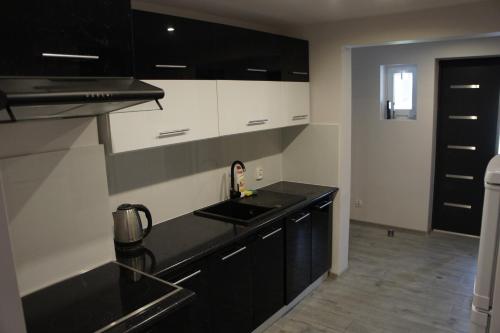 a kitchen with black and white cabinets and a sink at Pueblo Pokoje in Stegna