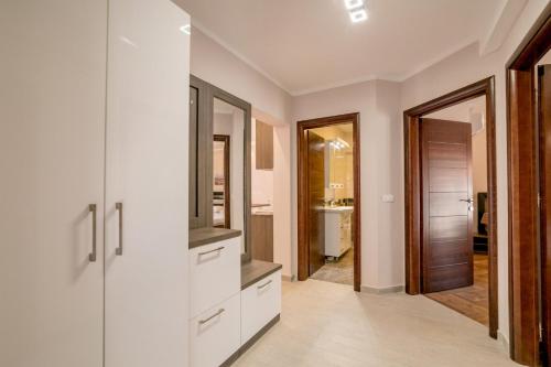 a kitchen with white cabinets and a large mirror at Apartmani Matej in Kotor