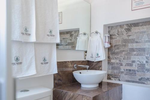 a bathroom with a sink and a toilet and towels at Real Naviero Hotel Ejecutivo in Manzanillo