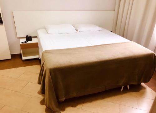 una camera da letto con un grande letto con lenzuola bianche di Hotel Belvedere Araras - By UP Hotel - Fácil Acesso Hospital São Leopoldo e Faculdades ad Araras