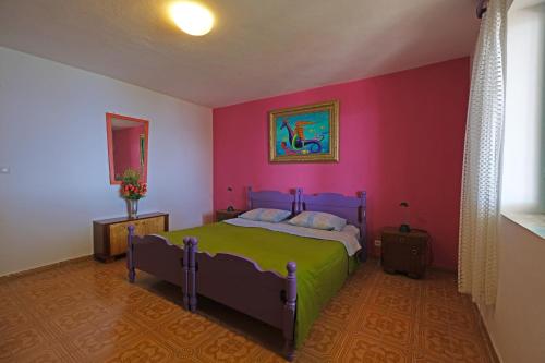 1 dormitorio con cama y pared de color rosa en The View Stara Baška en Stara Baška