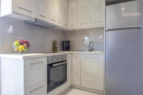 a kitchen with white cabinets and a bowl of fruit at zakynthos town modern roof apartment in Zakynthos Town