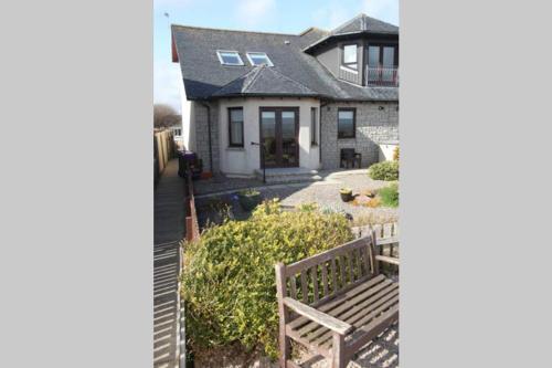a house with a wooden bench in front of it at BELL ROCK VIEW ARBROATH in Angus