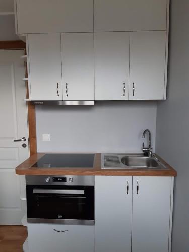 a kitchen with white cabinets and a stove and a sink at Kurzemītes apartamenti in Kuldīga