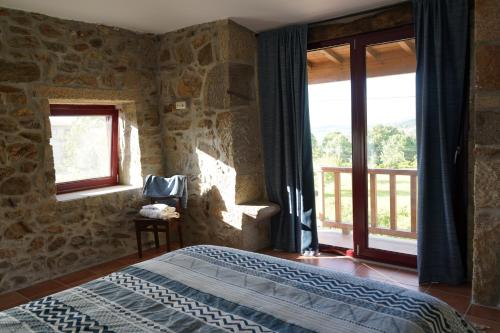 a bedroom with a bed in a room with windows at Casa da Belavista in Vilar de Nantes