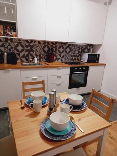 a kitchen with a wooden table with bowls and cups at Apartamenty Osmolice w Stawach in Dęblin