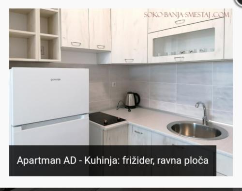 uma cozinha com armários brancos e um lavatório em Apartman AD em Sokobanja