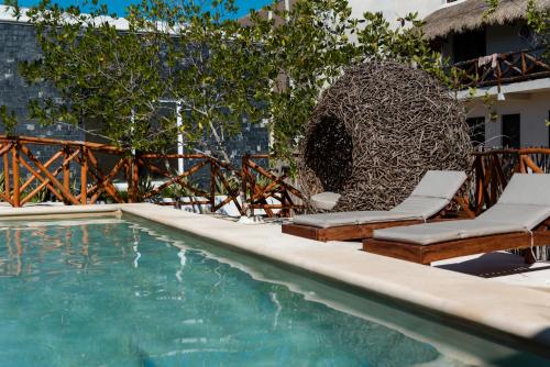 una piscina con due sedie a sdraio e una fontana di Sanyama Holbox a Isola Holbox