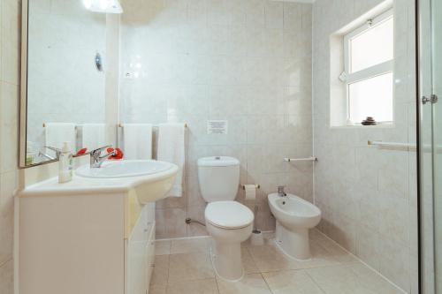 a white bathroom with a toilet and a sink at Apartment Tropicos in Carvoeiro
