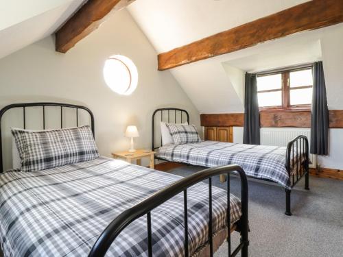 two beds in a room with a window at Cyffdy Cottage - Aran in Llanycil