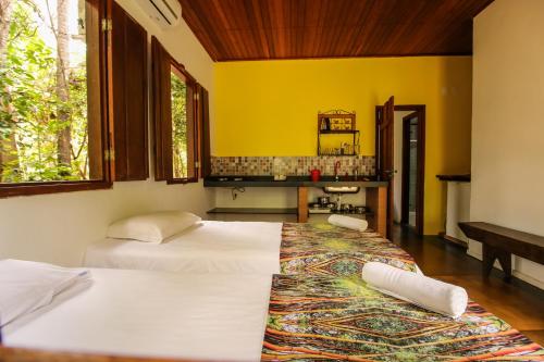 two beds in a room with yellow walls at Pousada Arvoredo in Pirenópolis
