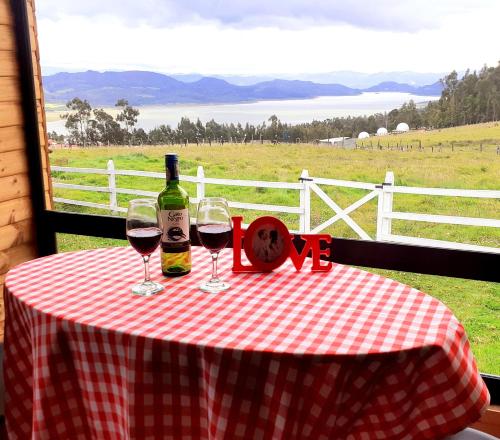 a table with two wine glasses and a bottle of wine at Cabañas Altos del Dorado in Guatavita