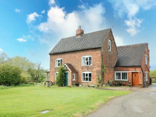 a large brick house with a green yard at The Mill Wheel in Ashbourne