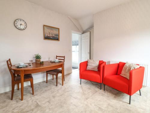 a living room with a table and two red chairs at The Mill Wheel in Ashbourne